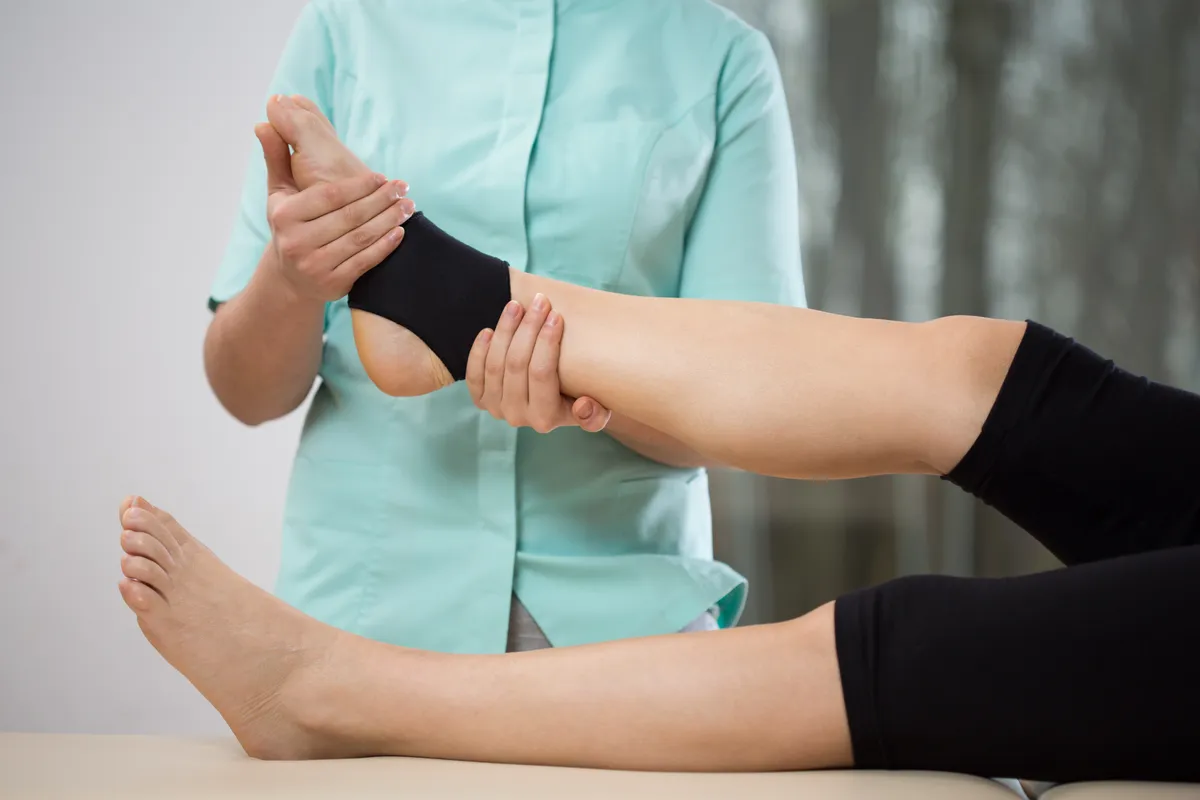 Young physiotherapist doing ankle manipulation to elderly woman